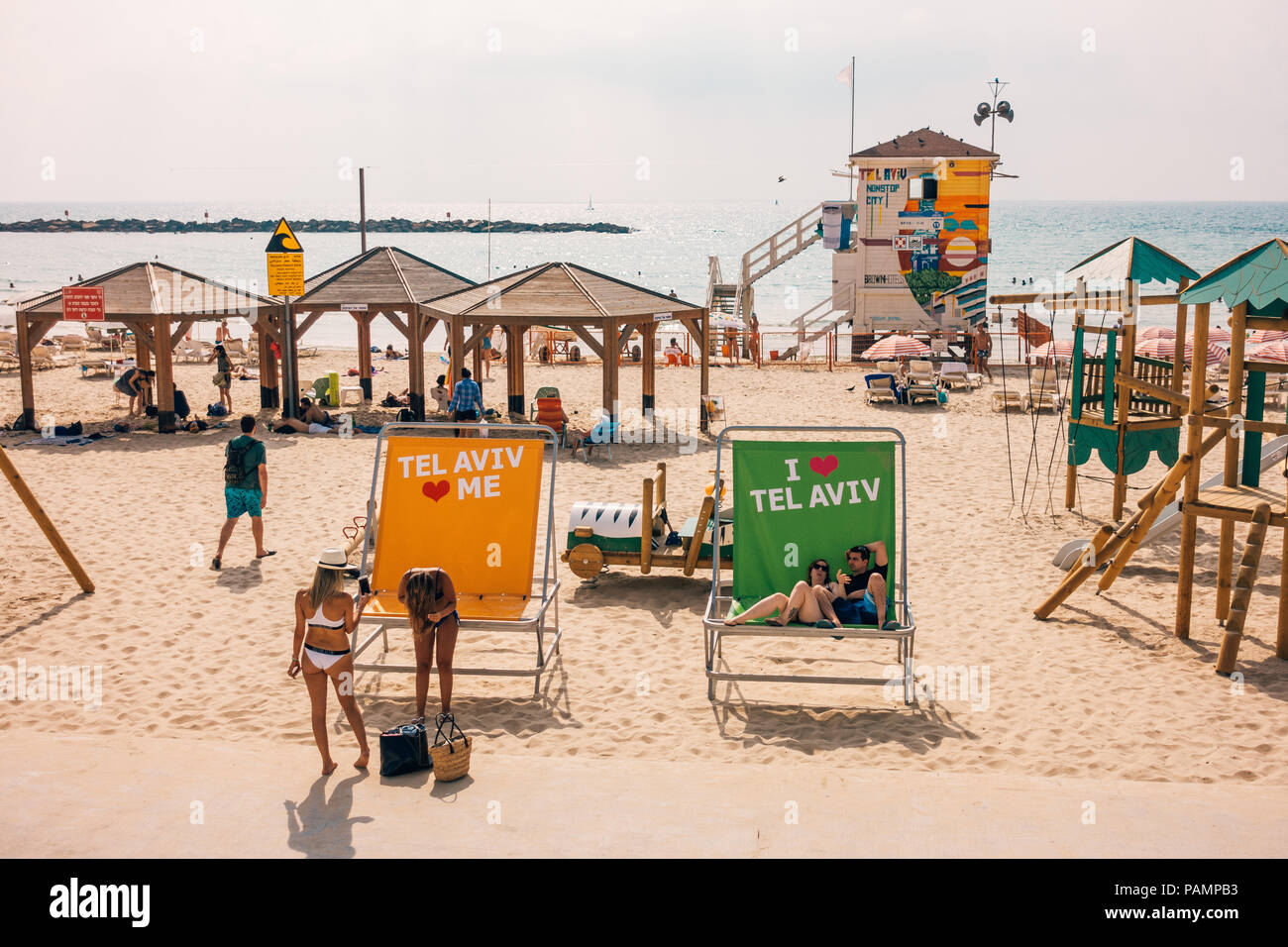 beachgoers relax in chairs and on the sand at the colourful Frishman Beach in Tel Aviv, Israel Stock Photo