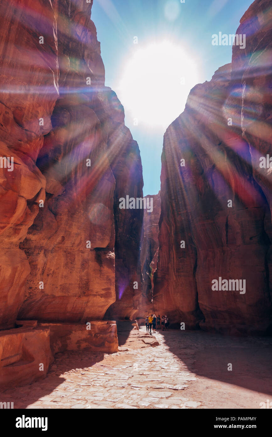Tourists are dwarfed by the narrow canyon walls on the walk into the Lost City of Petra, Jordan Stock Photo