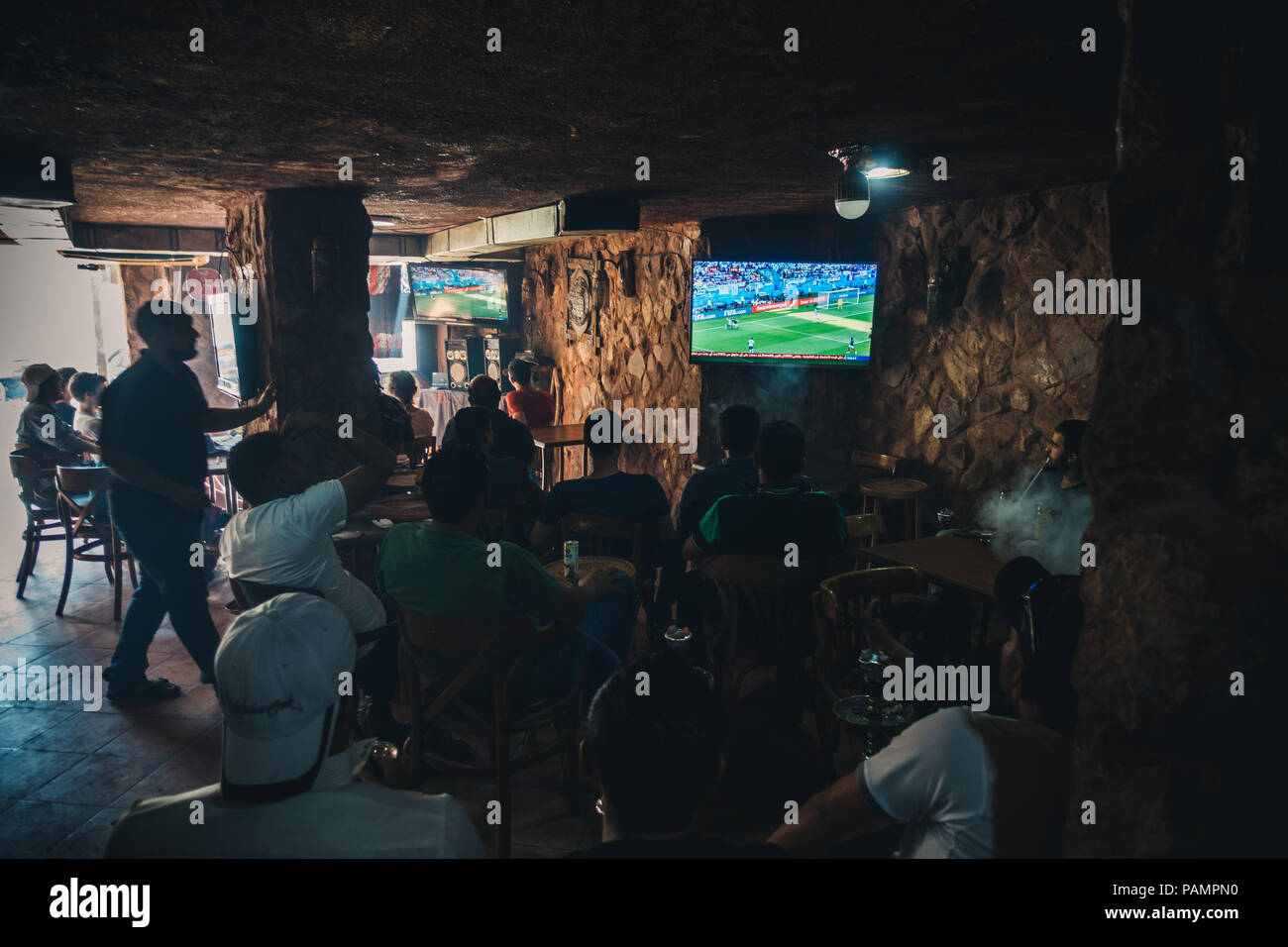 a group of Jordanian men smoke hookah and watch Argentina play France in the FIFA World Cup 2018 in a bar in Wadi Musa, Jordan Stock Photo