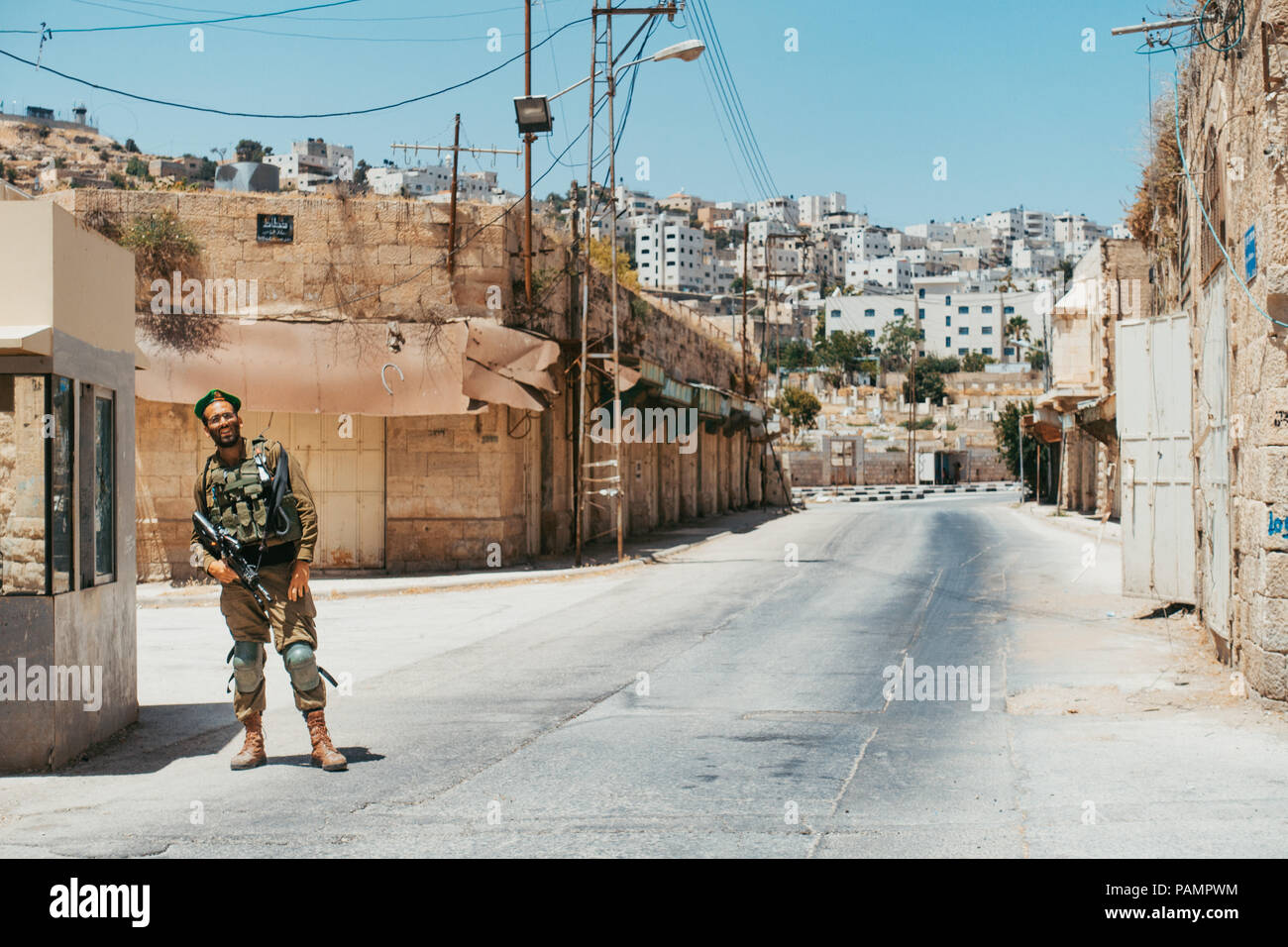 an Israel Defense Forces soldier stands guard prohibiting muslims from entering a Jews-only settlement in Hebron, Occupied West Bank Stock Photo