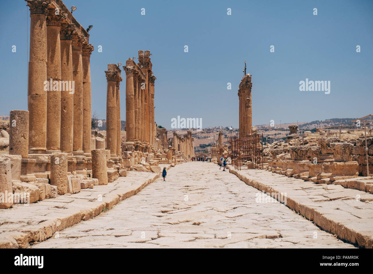 old ancient Greco-Roman columns line cobblestone streets on a warm summers day in Jerash, Jordan Stock Photo