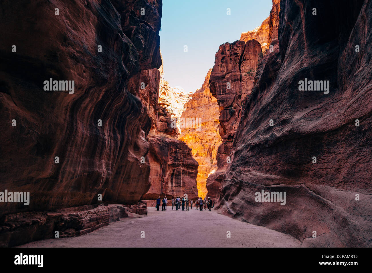 a tour group walks down the main path into Petra, Jordan. The canyon was carved by the rock splitting during an earthquake Stock Photo