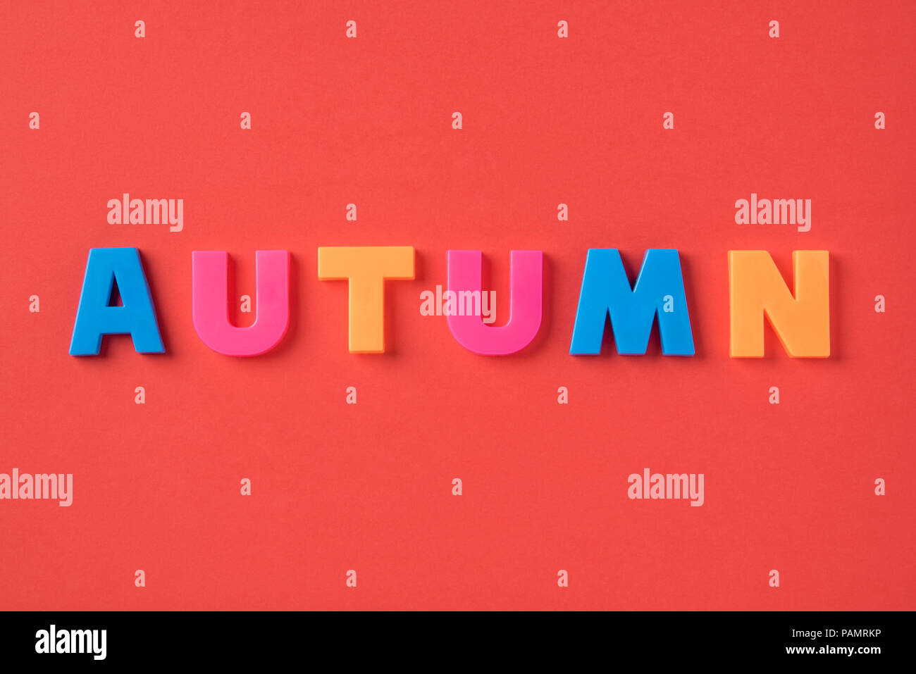 The autumn inscription with plastic letters on a red paper background