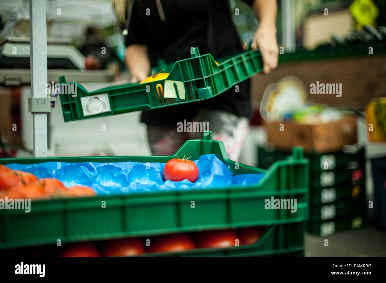 Woman pilling up tomato baskets at farmer's market Stock Photo
