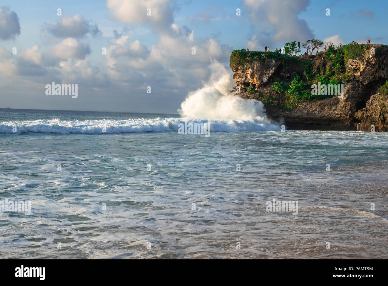 Sea waves splashing at the rocks in Bali, green lush nature surrounding