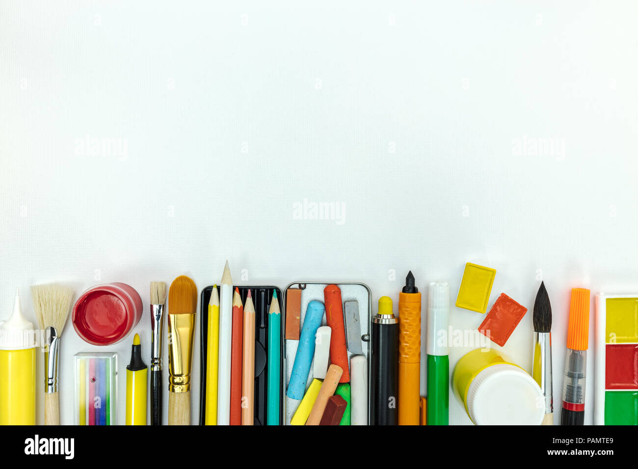 various school supplies and tools for painting. watercolor paints, pencils, crayon, brushes on white desk Stock Photo