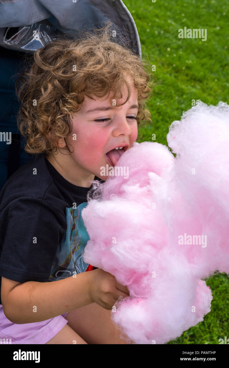 Young child enjoying ball of pink candy floss - France. Stock Photo