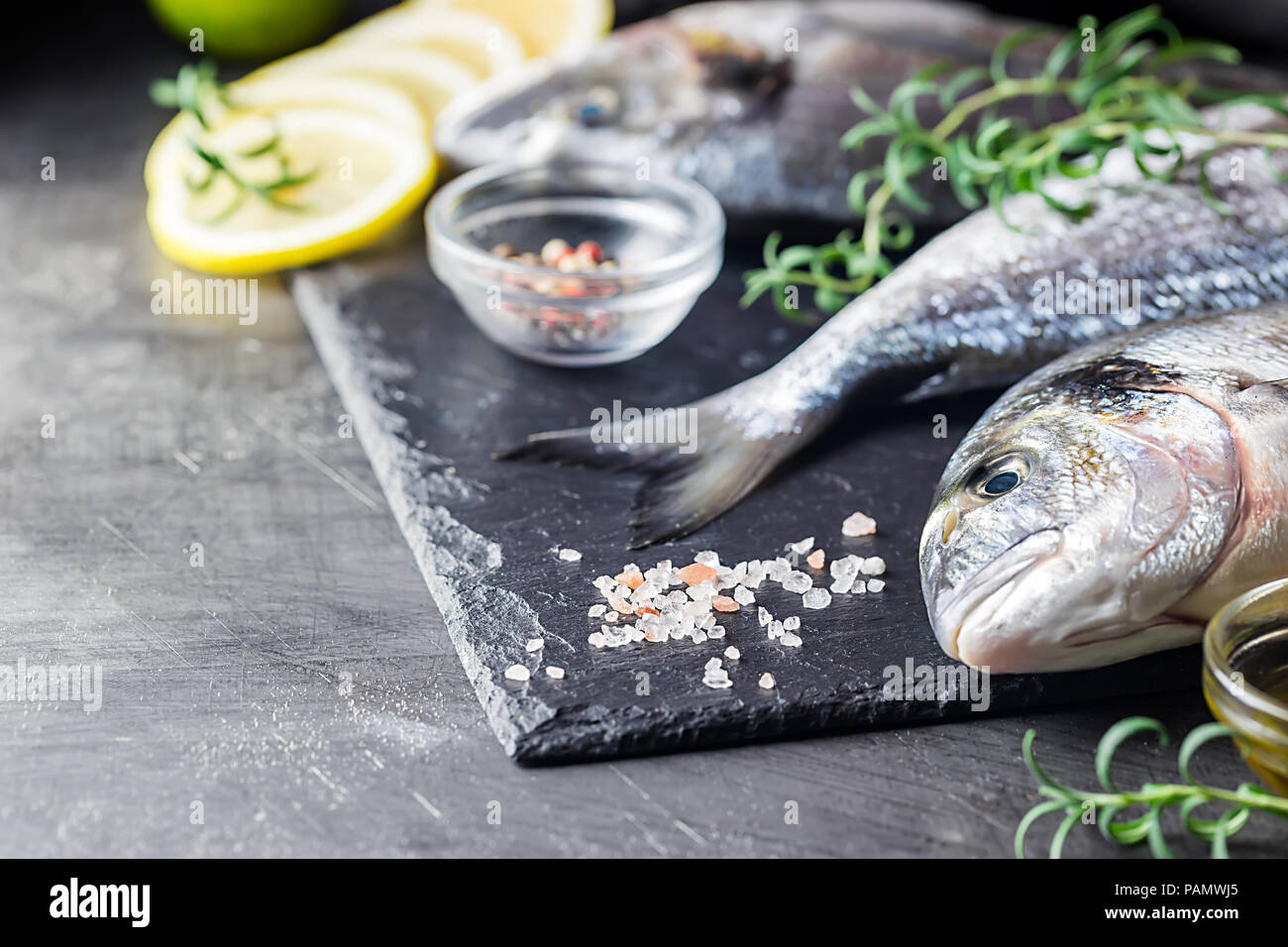 Fresh uncooked dorado or sea bream fish with lemon slices, spices and herbs. Mediterranean cuisine. Top view Stock Photo