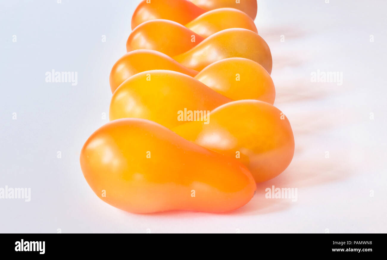 Pear drop tomatoes in a line , bright yellow color  food , light  shadows  ,white background  ,horizontal composition ,studio shot , Stock Photo