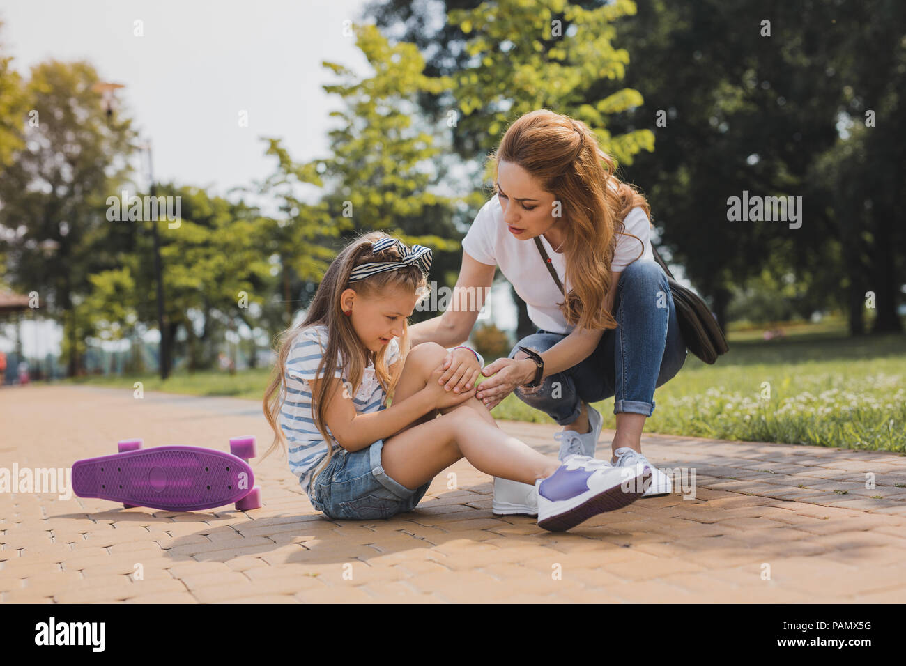 Caring mother hugging her active daughter after falling Stock Photo Alamy