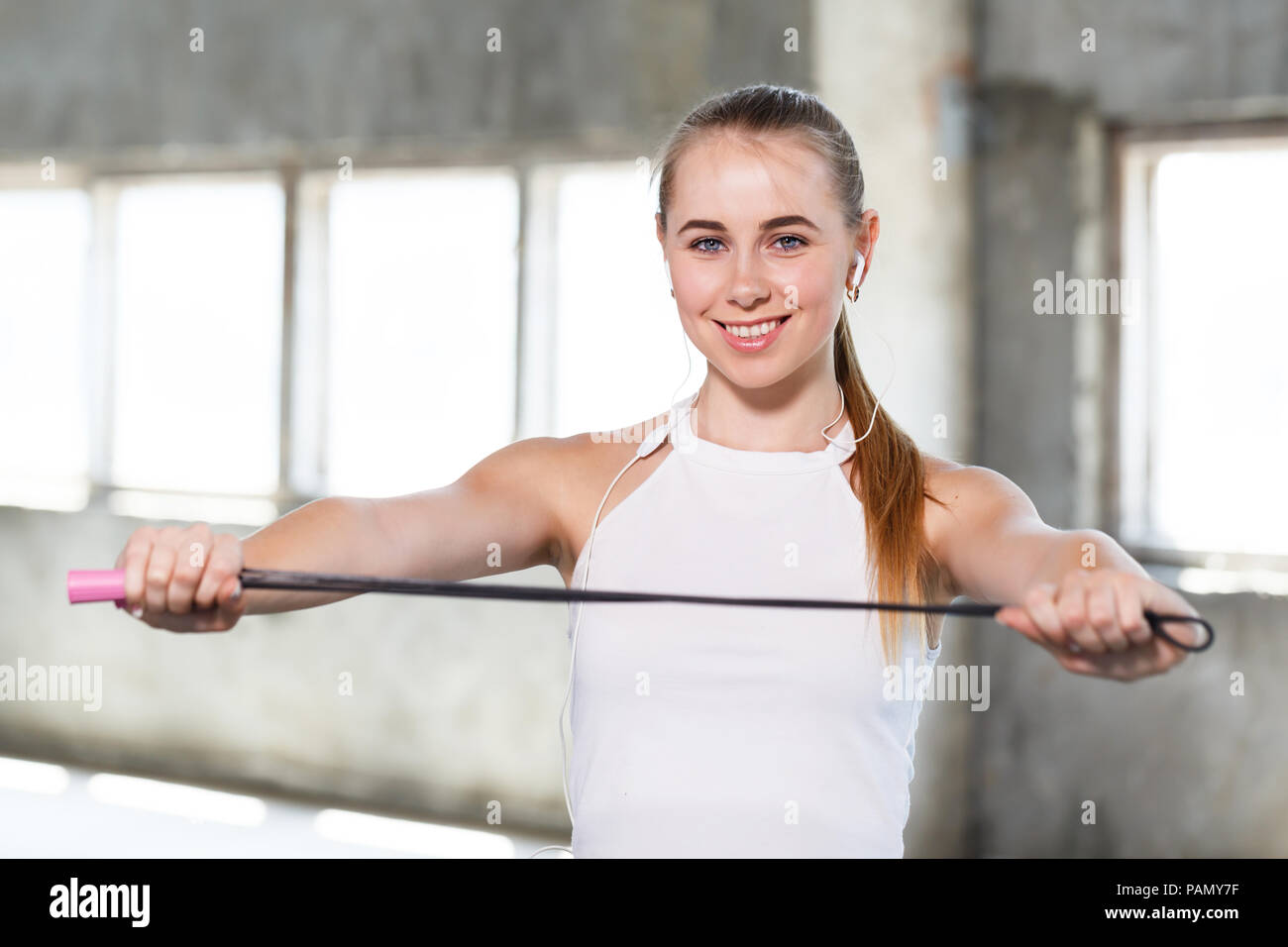 Happy fitness girl with perfect body shape enjoying training with rope  doing cardio exercises, positive young sportswoman skipping in white loft  gym on pilates workout Stock Photo - Alamy