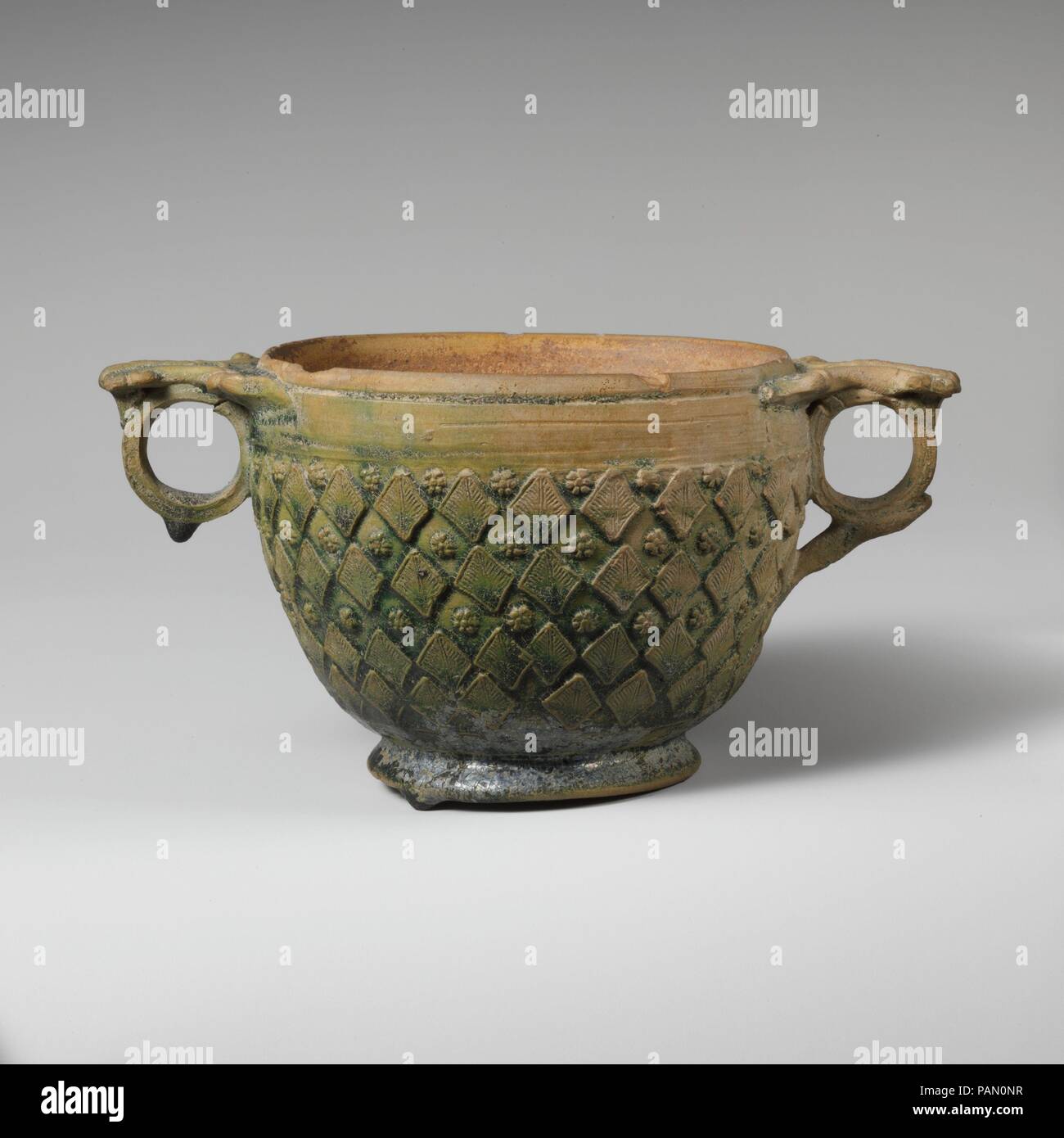 Terracotta scyphus (drinking cup). Culture: Roman. Dimensions: H. 3 in. (7.6 cm)  diameter  3 11/16 in. (9.4 cm). Date: 1st half of 1st century A.D..  Green-glazed with leaf decoration and rosettes. Museum: Metropolitan Museum of Art, New York, USA. Stock Photo