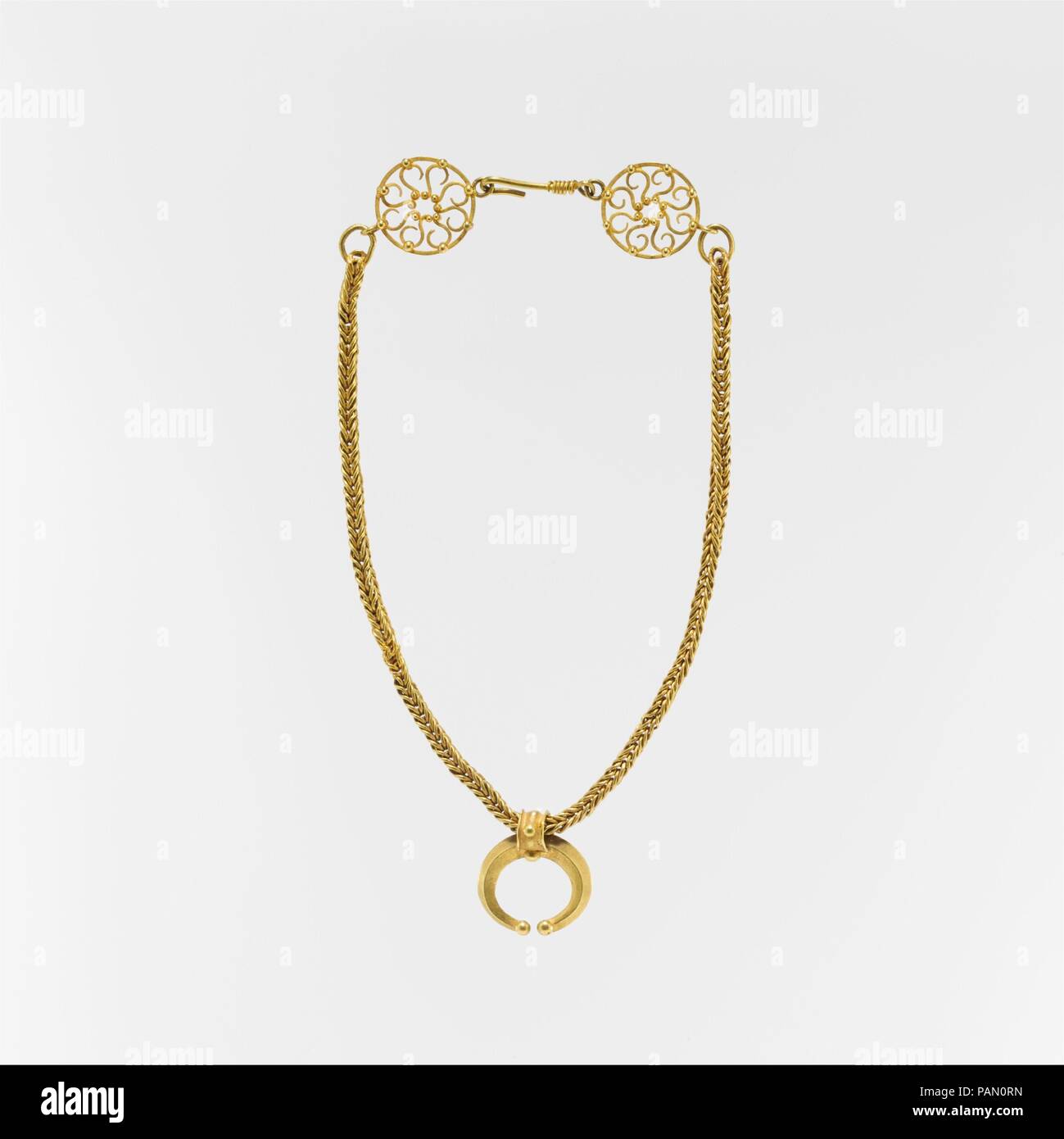 Gold necklace with crescent-shaped pendant. Culture: Roman. Dimensions: Other: 14 1/2 in. (36.8 cm). Date: 1st-3rd century A.D..  Some styles of Roman jewelry were both very long-lived and used throughout the Empire. The wheel-shaped finials and the crescent pendant, symbolic of the sun and moon, that decorate this necklace are found in jewelry from a hoard found in Britain dated to the mid-second century and in depictions on Roman mummy portraits from Egypt. Museum: Metropolitan Museum of Art, New York, USA. Stock Photo