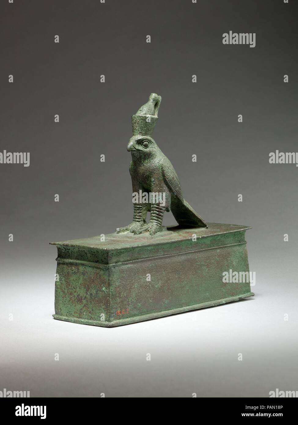 Falcon surmounting box for an animal mummy. Dimensions: H. 12.2 cm (4 13/16 in.); W. 4.5 cm (1 3/4 in.); L. 12.4 cm (4 7/8 in.). Date: 664-30 B.C..  The falcon god Horus stands with his wings swept back. He wears the double crown of Egypt, a royal crown that symbolizes the union of Lower and Upper Egypt, and highlights Horus' role as the legitimate ruler of the entire land. The crown's elements are distinct and well made: the red crown of Lower Egypt, lacking only its curling spiral at the front, and the white crown of Upper Egypt. The falcon wears the double crown because Horus and the concep Stock Photo
