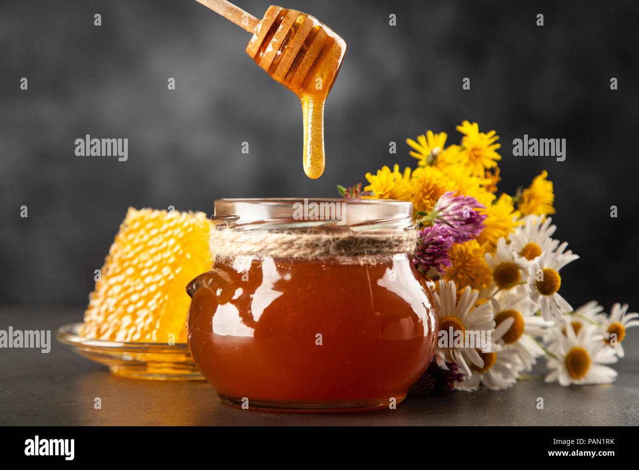 Honey jar and dipper with leaking honey Stock Photo Alamy