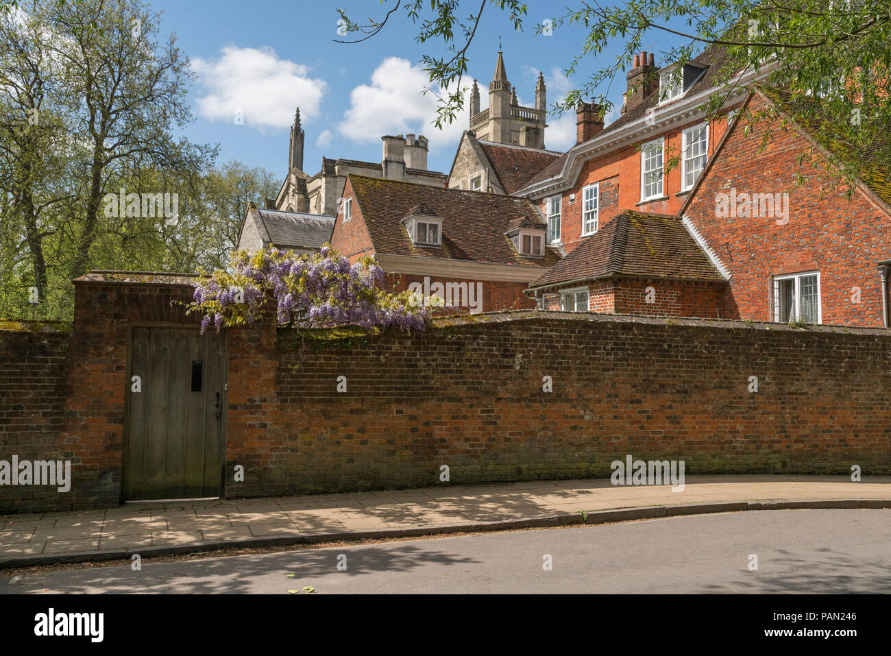 Buildings at the rear of Winchester College with wysteria growing over a wall with doorway within, Hampshire, England. Stock Photo