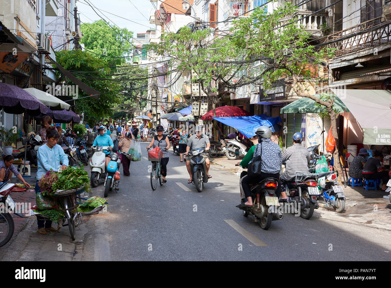 A traditional streert in Hanoi's Old Quarter, Vietnam, with street vendors, cyclists and moped riders. Stock Photo