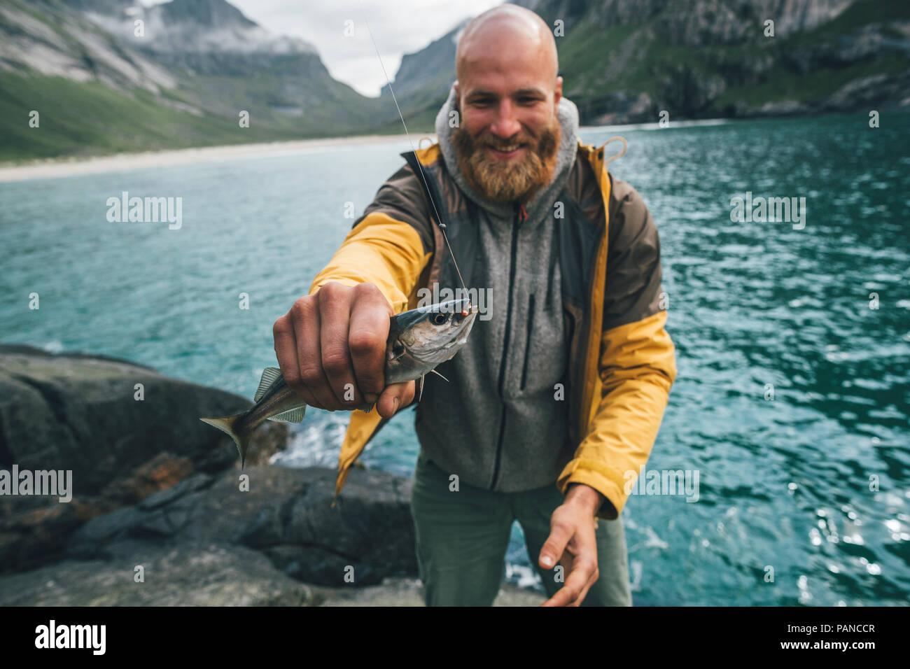 Norway, Lofoten, Moskenesoy, Young man holding freshly caught fish Stock Photo
