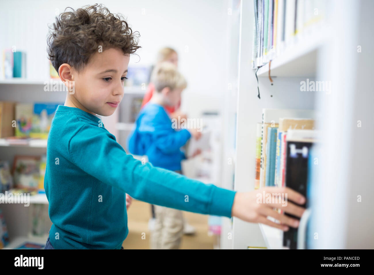 Schoolboy taking book from shelf in school library Stock Photo