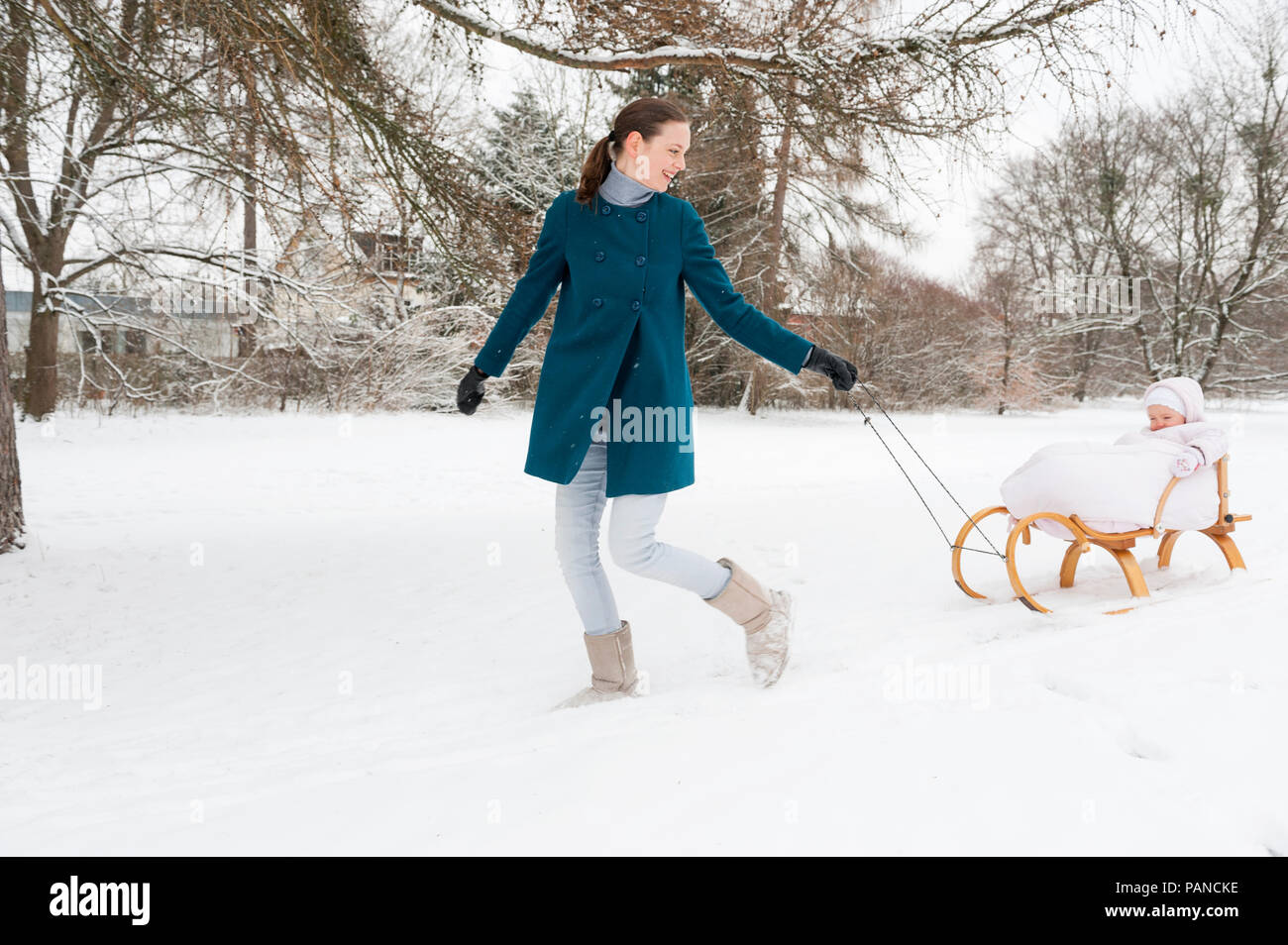 Mother pulling little daughter on sledge Stock Photo