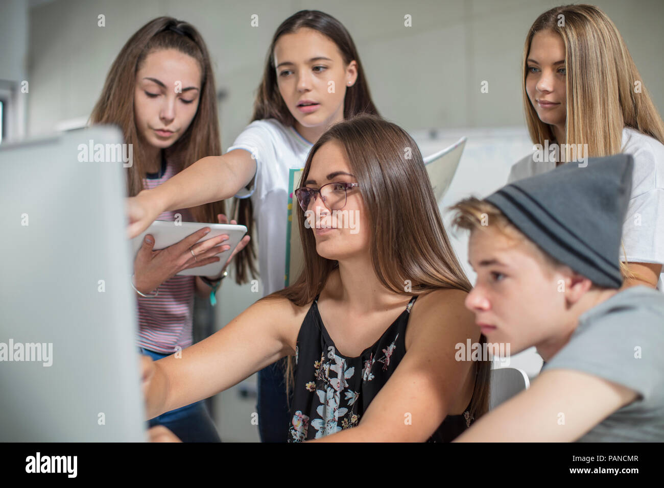 Teacher and students looking at computer screen together Stock Photo