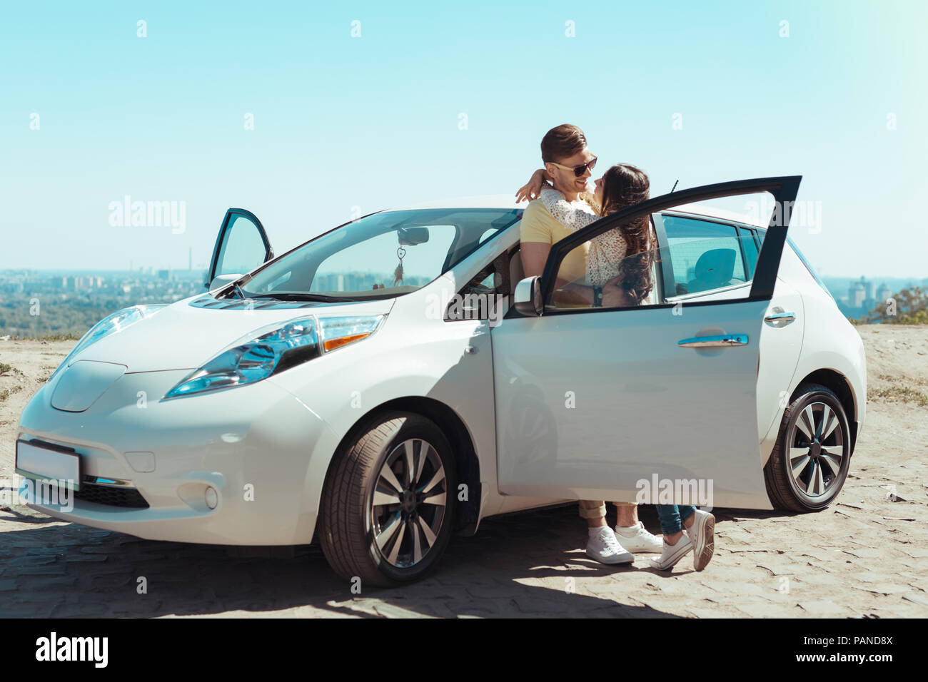 Stylish fashionable couple wearing white sneakers standing near car