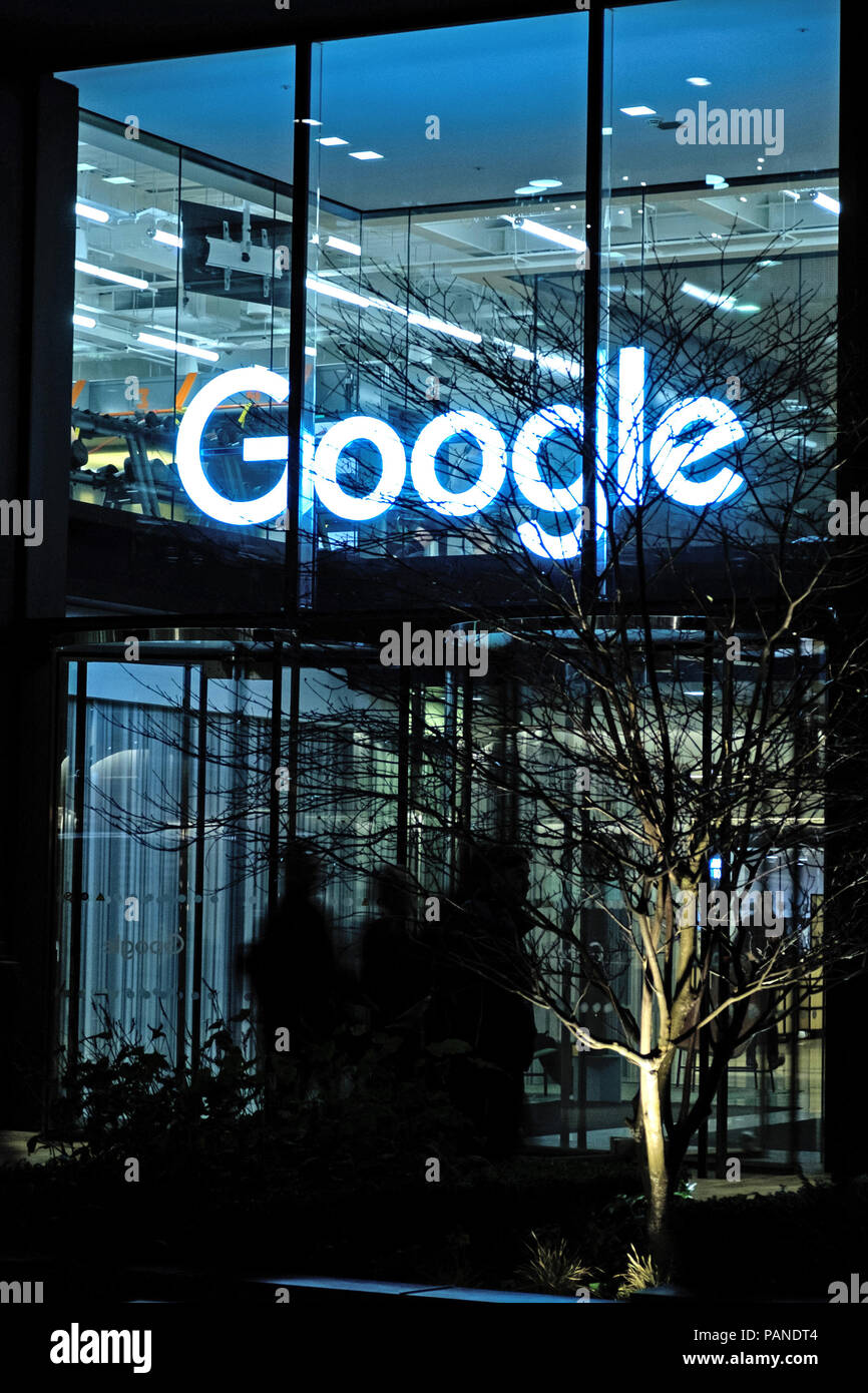The entrance to Google's new UK headquarters building in St Pancras Square, London with  Google sign above door. Night time, portrait. Stock Photo