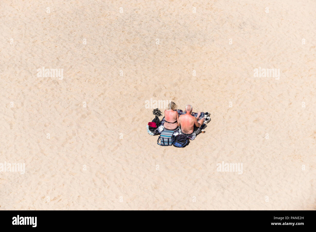 A mature couple holidaymakers visitors sunbathing on a beach in Newquay in Cornwall. Stock Photo