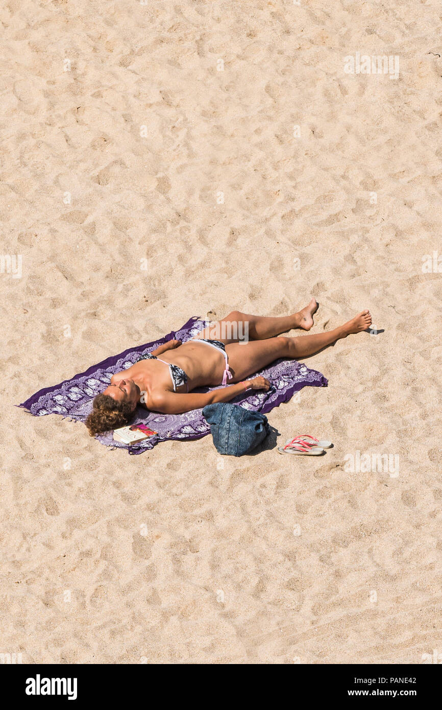 An attractive woman female holidaymaker sunbathing on a beach in Newquay Cornwall. Stock Photo