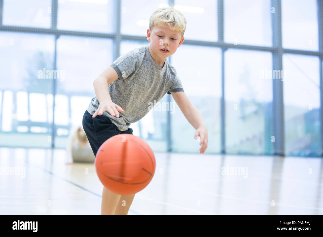 Schoolboy playing basketball in gym class Stock Photo