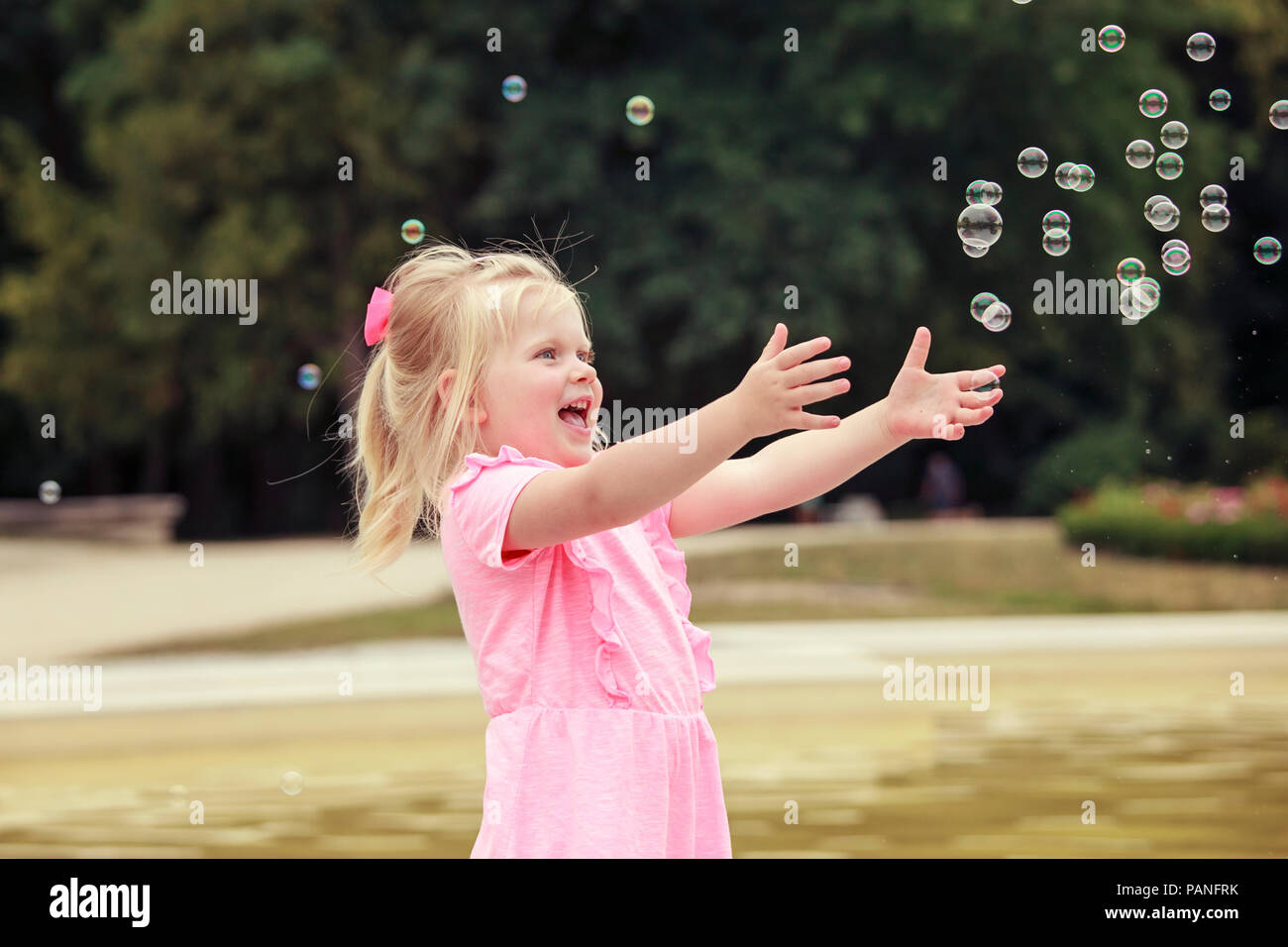 Three years old girl playing with soap bubbles Stock Photo