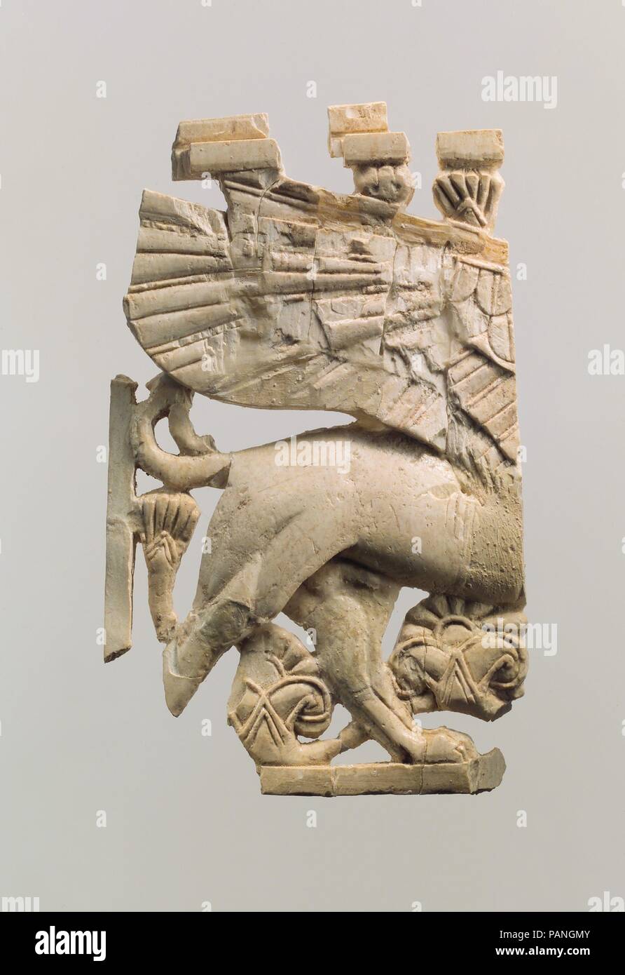 Openwork furniture plaque with sphinx. Culture: Assyrian. Dimensions: 4.06 x 2.44 x 0.39 in. (10.31 x 6.2 x 0.99 cm). Date: ca. 9th-8th century B.C..  During the early first millennium B.C., ivory carving was one of the major luxury arts that flourished throughout the ancient Near East. Elephant tusks were carved into small decorative objects such as cosmetic boxes and plaques used to adorn wooden furniture. Gold foil, paint, and semiprecious stone and glass inlay embellishments enlivened these magnificent works of art. Based on certain stylistic, formal, and technical characteristics also vis Stock Photo