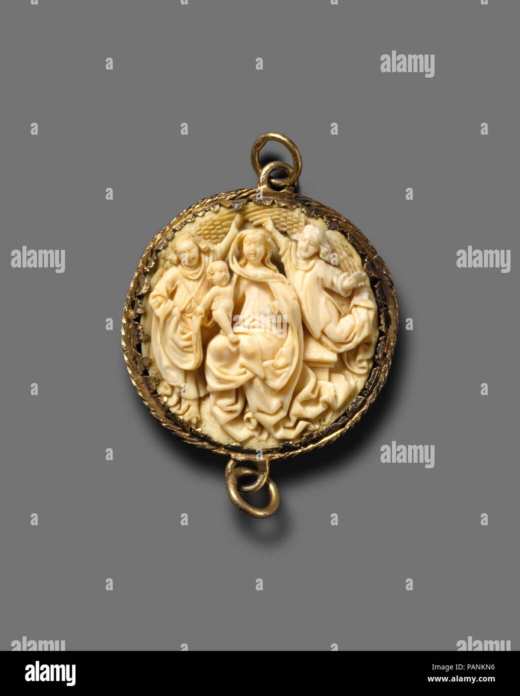 Pendant with the Coronation of the Virgin. Culture: North Netherlandish. Dimensions: 1 3/4 x 3/8 in. (4.4 x 0.9 cm). Date: 1450-1500.  The iconography of this roundel pendant of the Virgin Mary holding the Christ Child while being crowned by two angels refers both to the Virgin's role as the Queen of Heaven and to the Immaculate Conception. While the style is analogous to that of several examples of larger-scale sculpture variously attributed to Hainaut, Brabant, or  Gelderland, the composition suggests an awareness of contemporary engraving on the subject--notably that by Wenzel von Olmütz, w Stock Photo