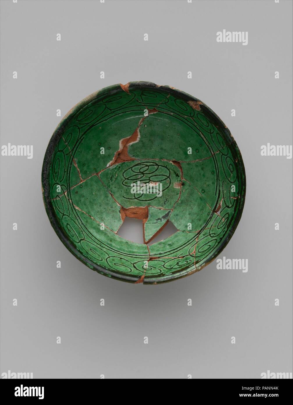 Green Glazed Bowl with Incised Decoration. Dimensions: H. 1 7/8 in. (4.8 cm)  Diam. 5 3/16 in. (13.2 cm). Date: 9th century.  A very unusual object in the Nishapur finds, the decoration of this bowl was decorated made by scratching a design into white slip and then dipping the vessel into a transparent green glaze. The production of this bowl cannot be attributed with certainty to a specific location. Museum: Metropolitan Museum of Art, New York, USA. Stock Photo