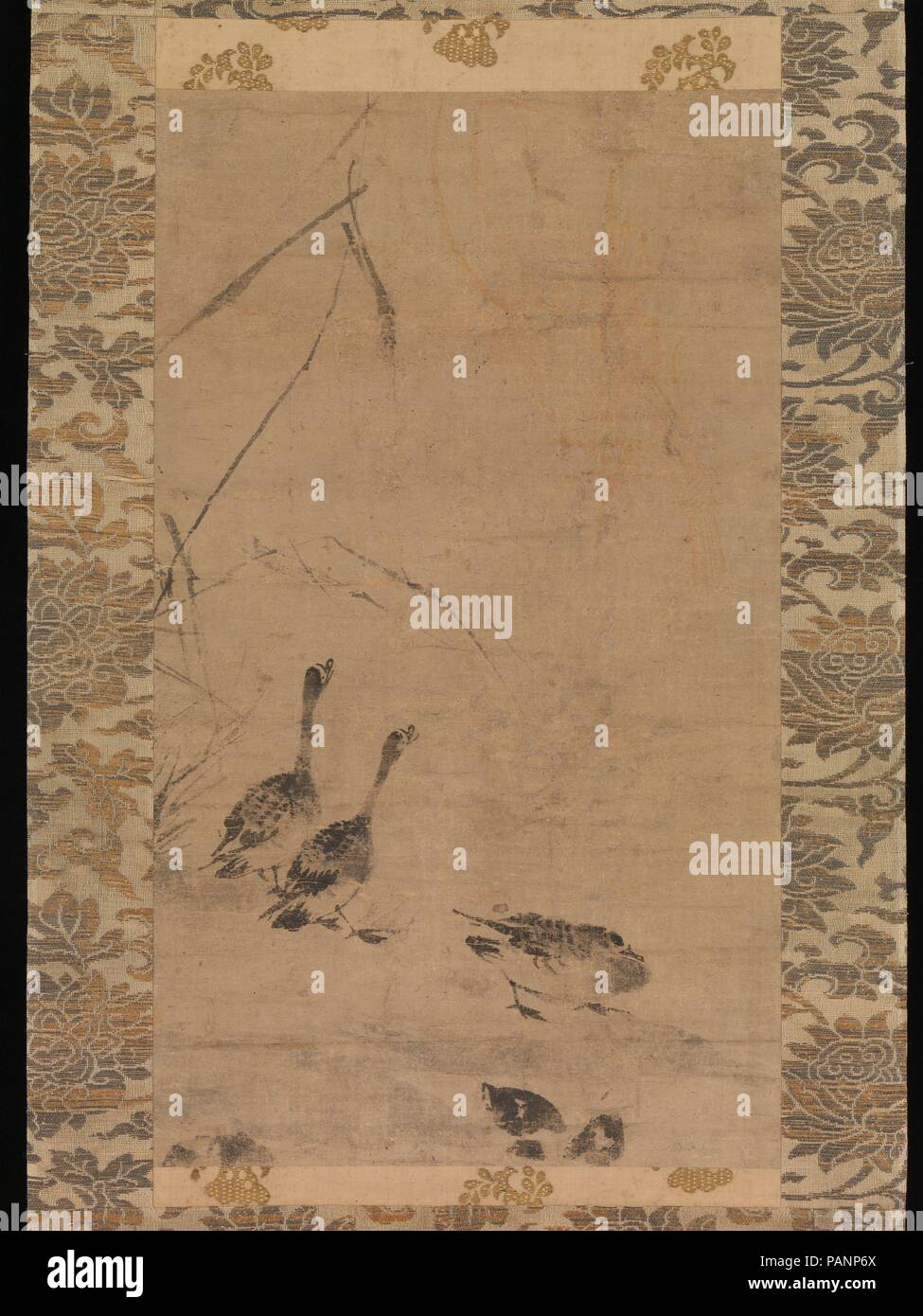 Geese and Reeds. Culture: Japan. Dimensions: Image: 19 5/8 × 11 7/16 in. (49.8 × 29 cm)  Overall with mounting: 50 7/8 × 15 15/16 in. (129.3 × 40.5 cm)  Overall with knobs: 50 7/8 × 17 7/8 in. (129.3 × 45.4 cm). Date: late 14th century.  It is near the end of autumn and three geese have alighted on a sandbank, indicated only by faint washy brushstrokes, with drier, darker strokes delineating withered reeds at the water's edge. One goose is at rest while the others crane their necks to call at the sky, perhaps signaling others in their flock who have begun their journey south.   The pictorial c Stock Photo