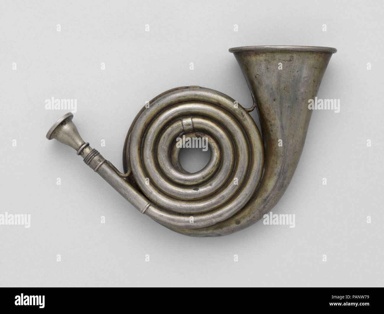 Pocket Post Horn in G. Culture: Italian. Dimensions: Height: 4 13/16 in. (12.3 cm)  Diameter: 2 15/16 in. (7.5 cm). Maker: Giuseppe Pelitti (Italian, Varese 1811-1865 Milan). Date: ca. 1880.  This horn is 5 ½ feet long, but its tightly coiled tubing and small, oval-shaped bell enabled it to be carried with ease in a pocket. This compact form of the horn was used for the 'small hunt' of rabbits, squirrels and other small game pursued on foot. Museum: Metropolitan Museum of Art, New York, USA. Stock Photo