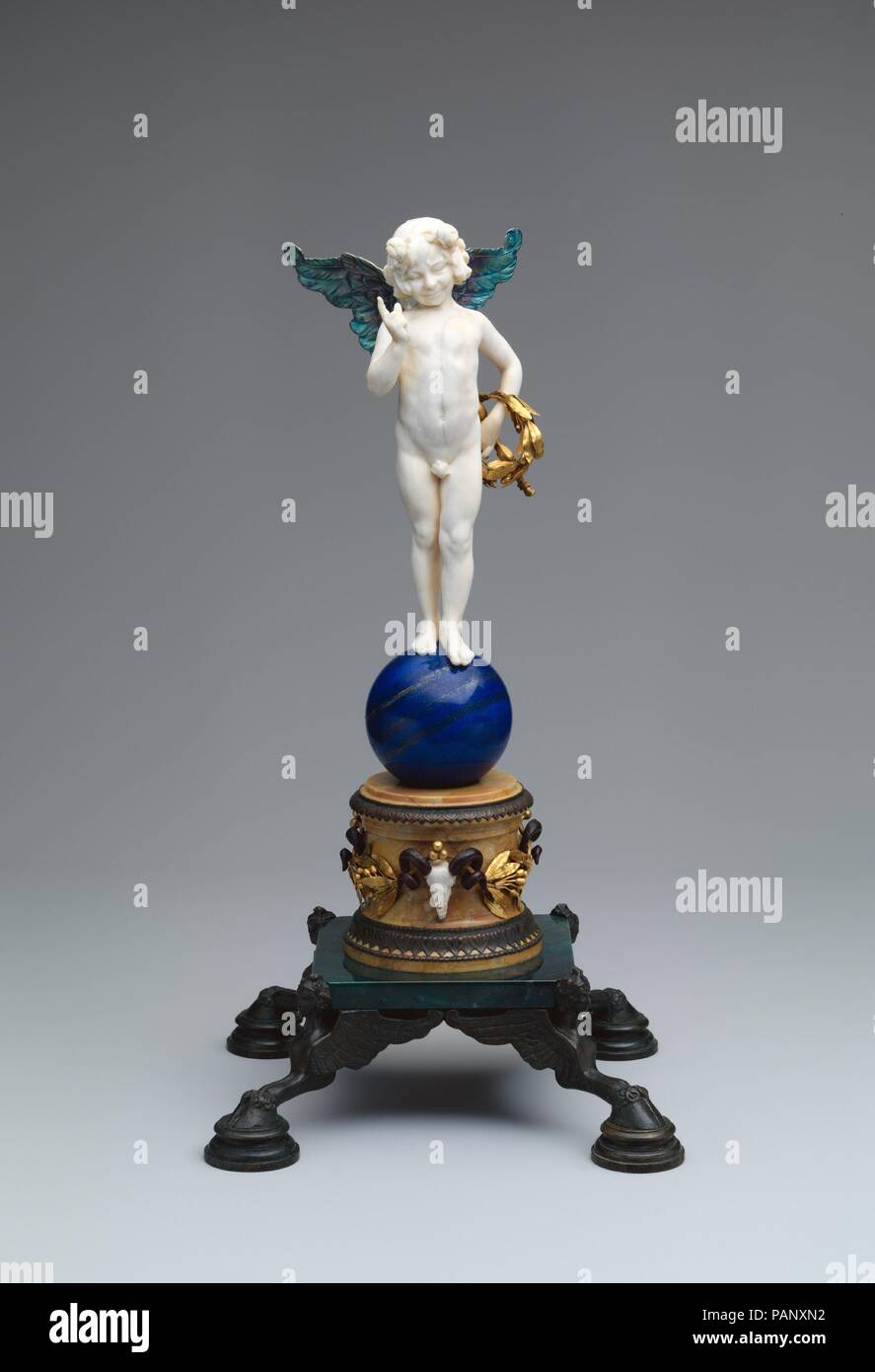Cupid. Artist: Frederick William MacMonnies (American, New York 1863-1937 New York). Dimensions: 16 1/8 in. height (41 cm) x  8 3/8 in. width (21.3 cm.) x 8 1/4 in. depth (21 cm.). Date: 1898.  Along with a number of French contemporaries, Paris-based MacMonnies participated in a late-nineteenth-century revival of interest in polychromy and mixed materials for sculpture. This unique multi-material object features an intricate play of diverse media: a fanciful carved ivory cupid with enameled silver wings surmounts an elaborate base incorporating colored stones, gold, bronze, and wood. MacMonni Stock Photo