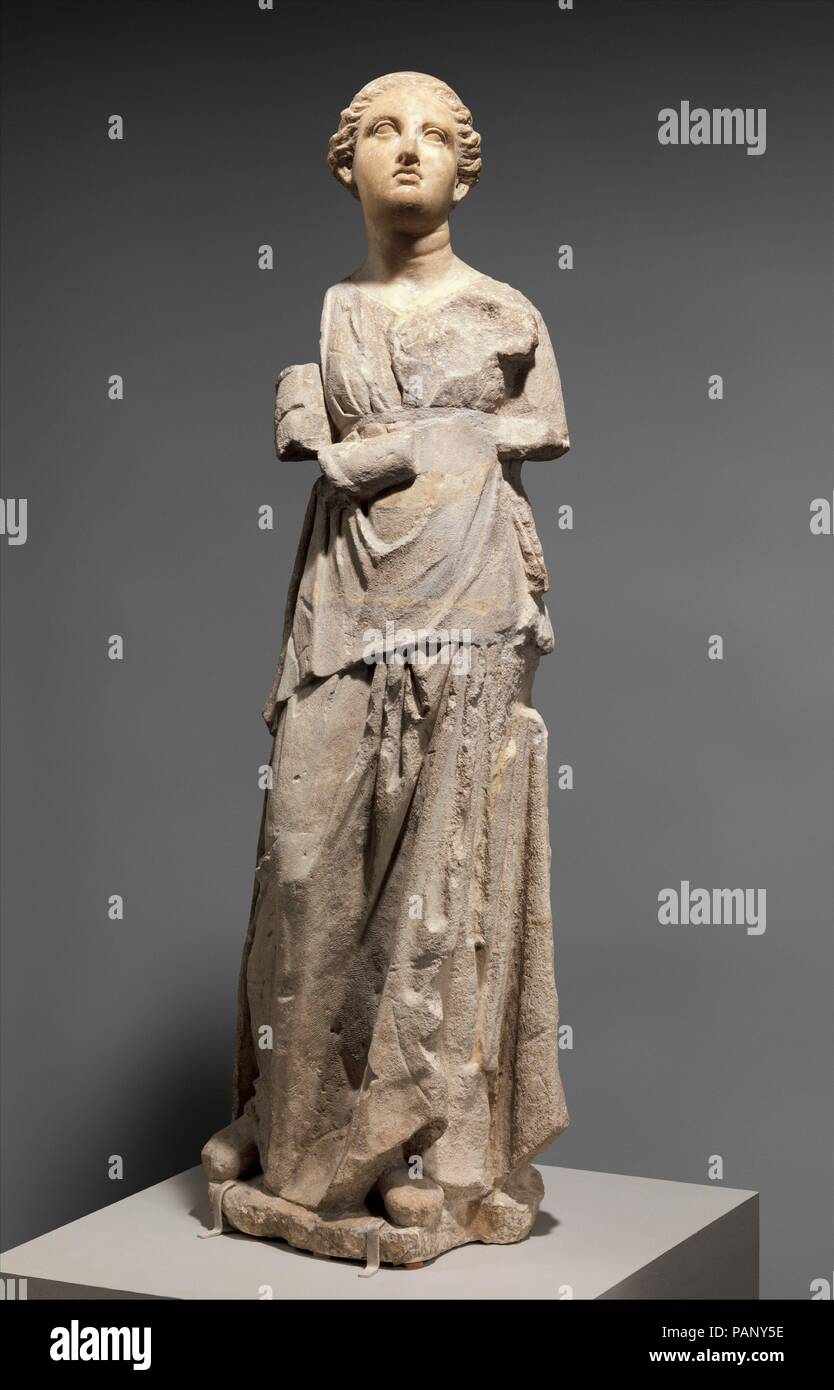 Marble and limestone statue of an attendant. Culture: Greek, South Italian, Tarentine. Dimensions: H.: 48 7/16 in. (123 cm). Date: late 4th or 3rd century B.C..  This young woman held an object in her right hand, perhaps a fan. The statue was originally likely part of a funerary group of an aristocratic woman with her attendant that would have served as a tomb marker. It was not uncommon during the Hellenistic period in Southern Italy to carve the heads of significant commissions in imported marble and use local limestone for the bodies. The Greek city of Tarentum had a particularly distinctiv Stock Photo