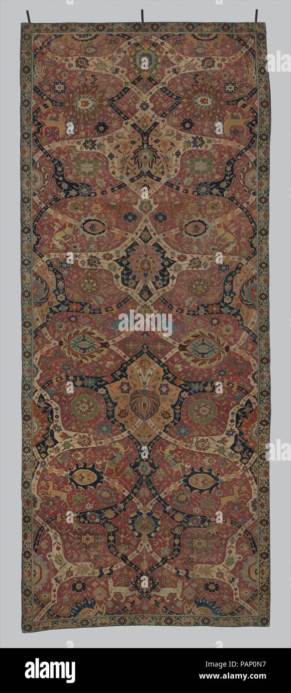 Carpet. Dimensions: Rug: L. 241 in. (612.1 cm)  W. 98 1/4 in. (249.6 cm). Date: early 17th century.  From the sixteenth century on, court and travelers' accounts mention the city of Kirman as a production and export center of high-quality carpets, known for their rich color palette and sturdy structure. Bold interlaced arabesque bands in blue and white and dense floral patterns add to a field containing stylized dragonlike creatures, deer, and lions. Museum: Metropolitan Museum of Art, New York, USA. Stock Photo