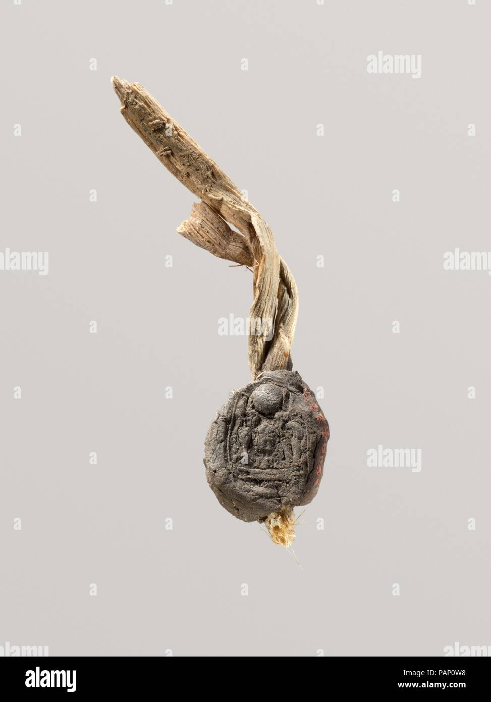 Seal Impression Attatched to a Fiber Tie from Tutankhamun's Embalming Cache. Dimensions: Seal and tie: L. 12 cm (4 3/4 in.)  Seal: L. 2.5 cm (1 in.); W. 2 cm (13/16 in.). Dynasty: Dynasty 18. Reign: reign of Tutankhamun. Date: ca. 1336-1327 B.C..  This mud sealing has similar to that on 09.184.262. Museum: Metropolitan Museum of Art, New York, USA. Stock Photo
