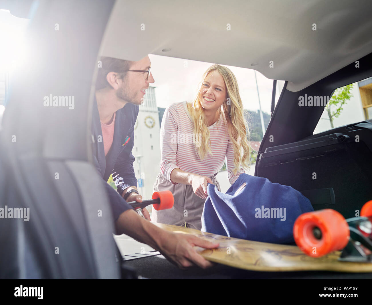 Smiling couple loading boot of electric car Stock Photo