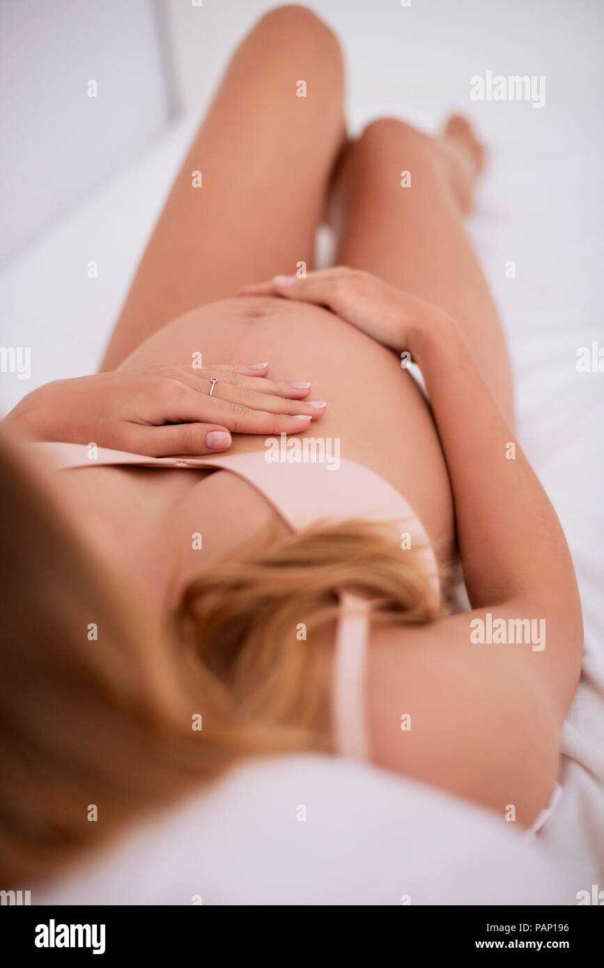 Pregnant woman lying on bed Stock Photo