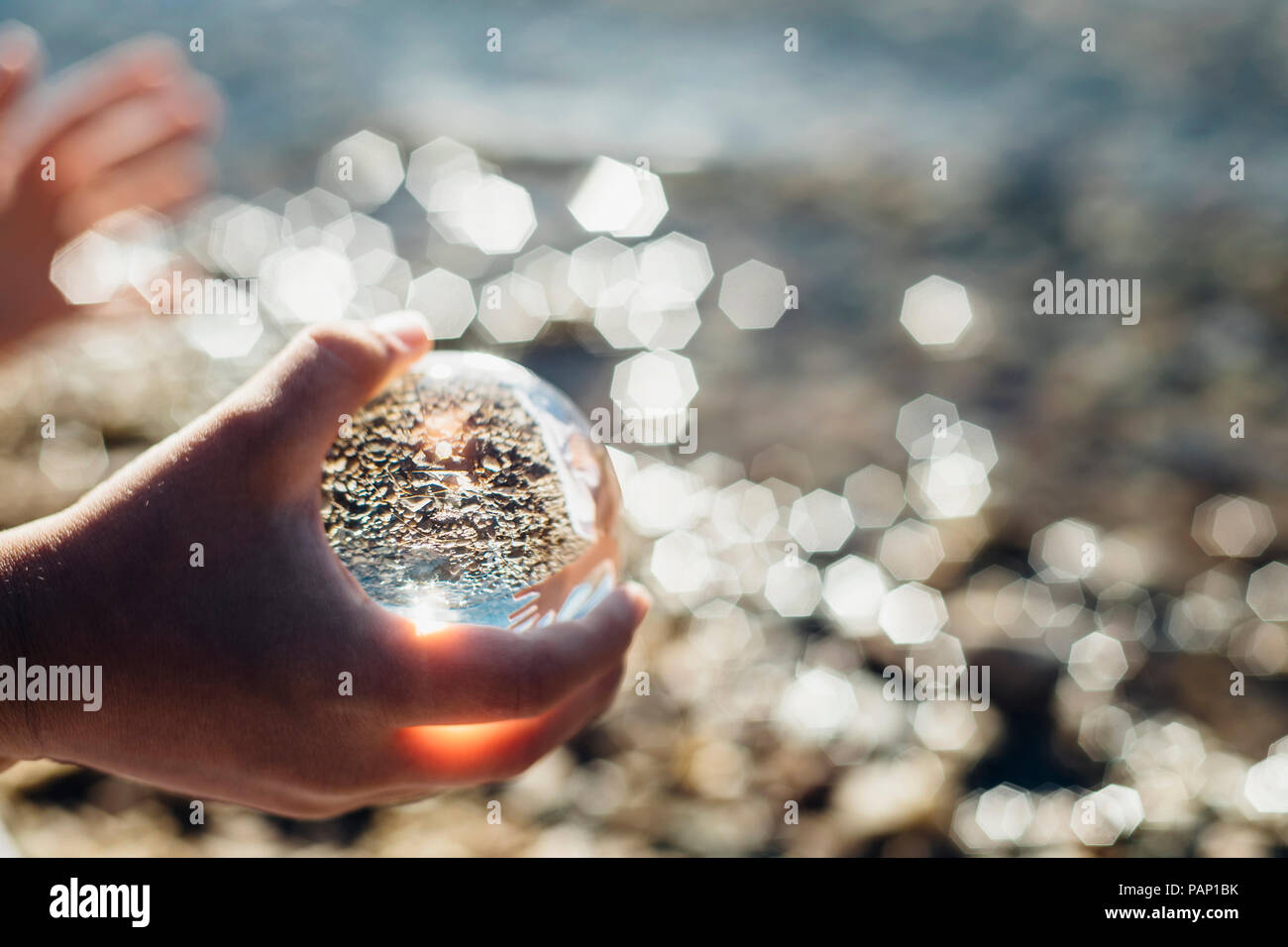 Boy's hand holding tansparent sphere at a lake Stock Photo