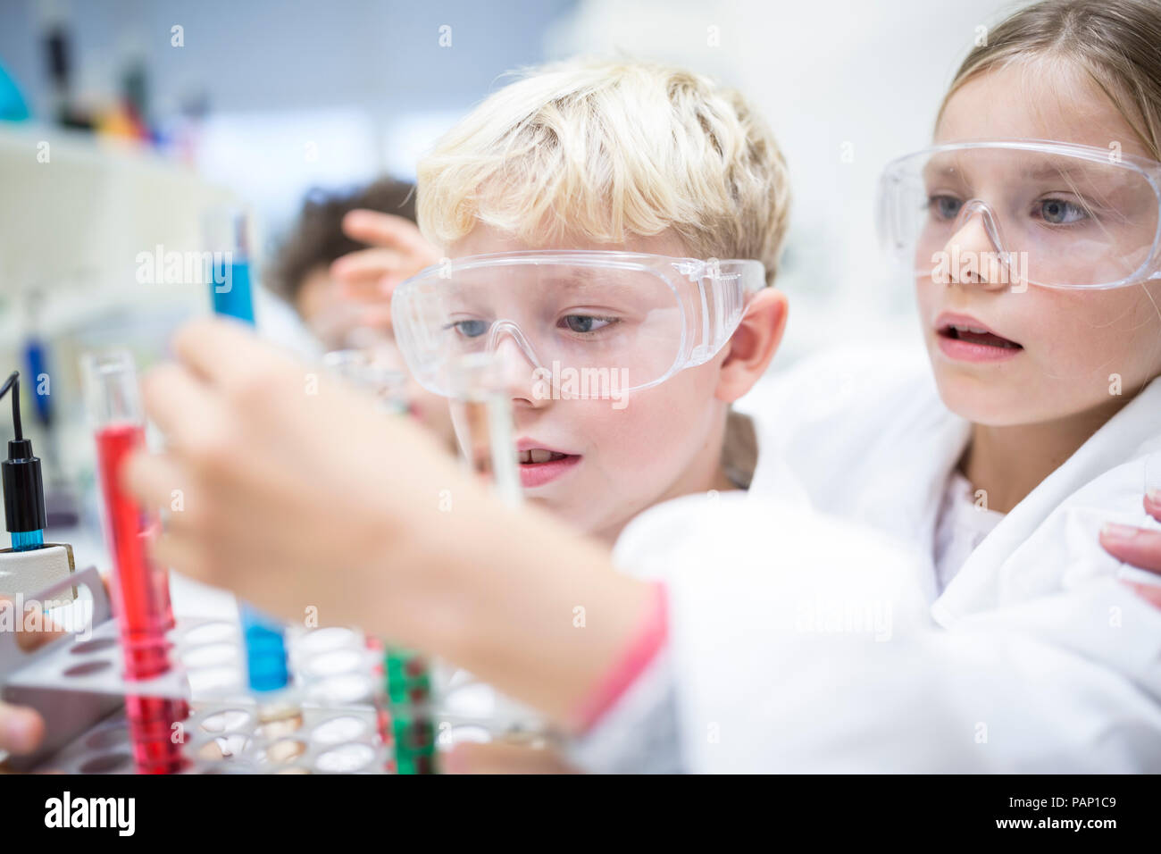Pupils in science class experimenting with liquids in test tubes Stock Photo