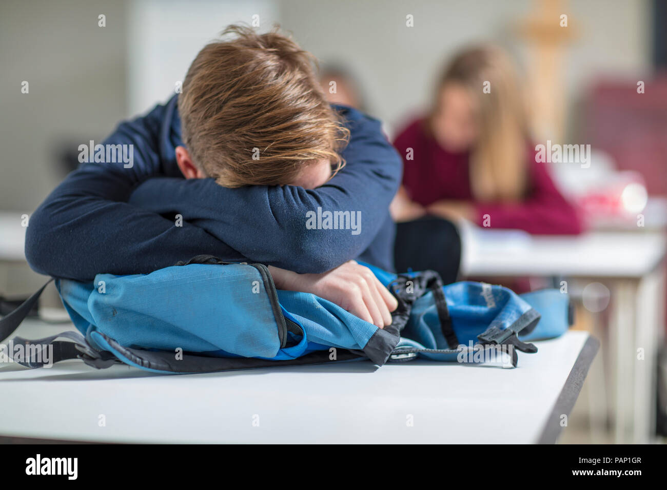 Teenage boy sleeping in class Stock Photo