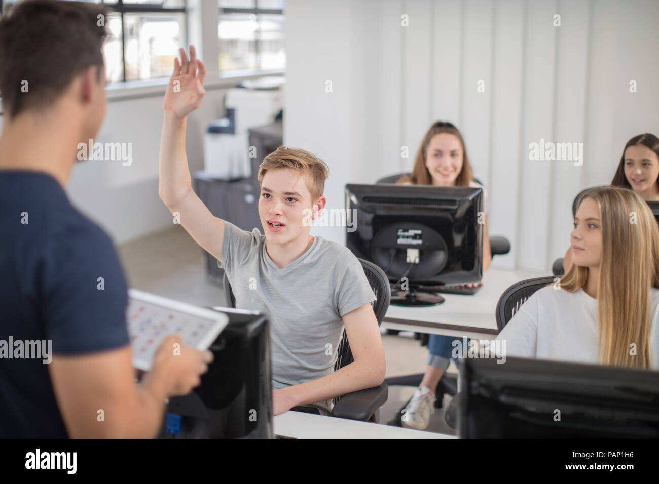 Boy raising hand in computer class Stock Photo