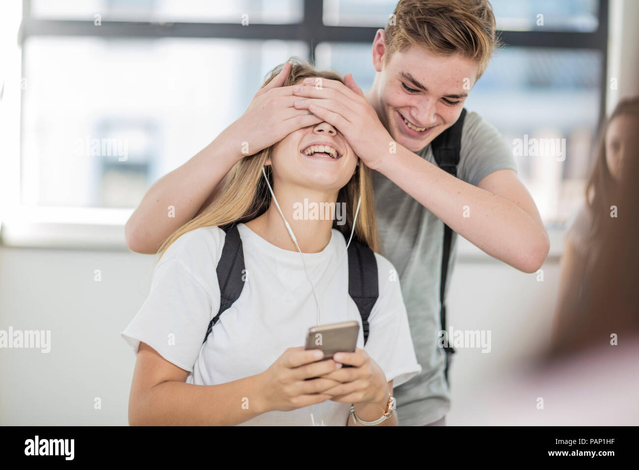 Boy covering girl's eyes in school Stock Photo