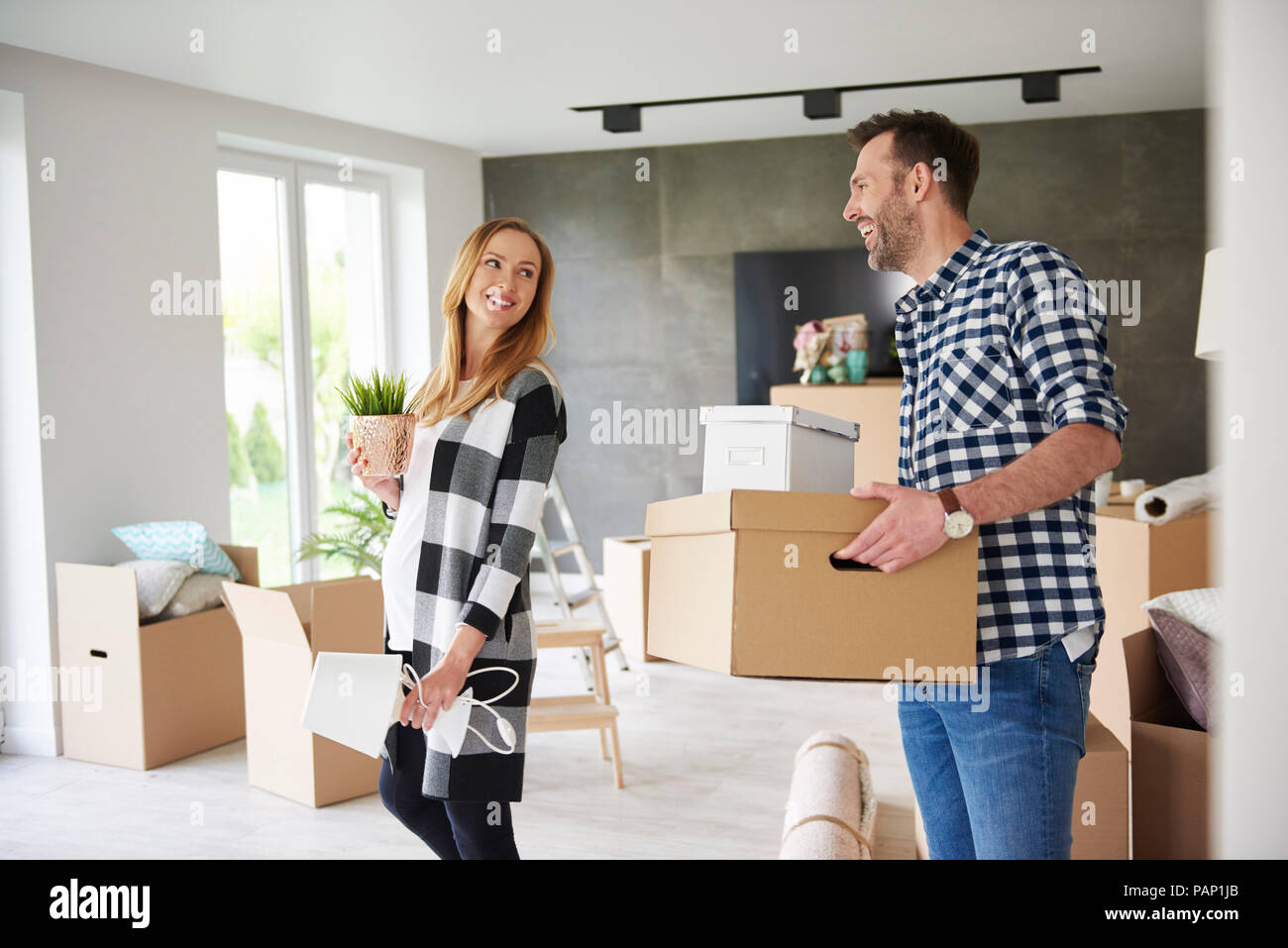 Happy couple moving house carrying cardboard box and plant Stock Photo ...