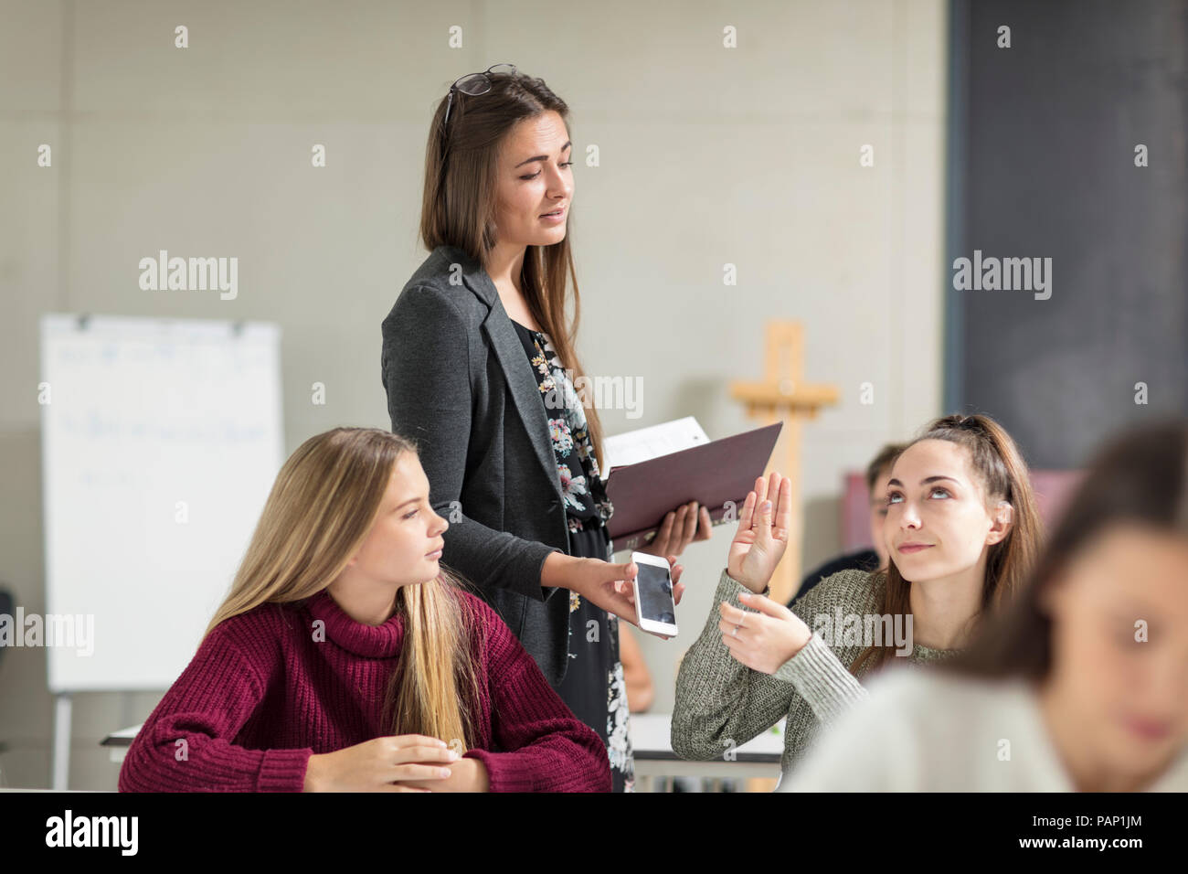 Teacher taking cell phone away from teenage girl Stock Photo