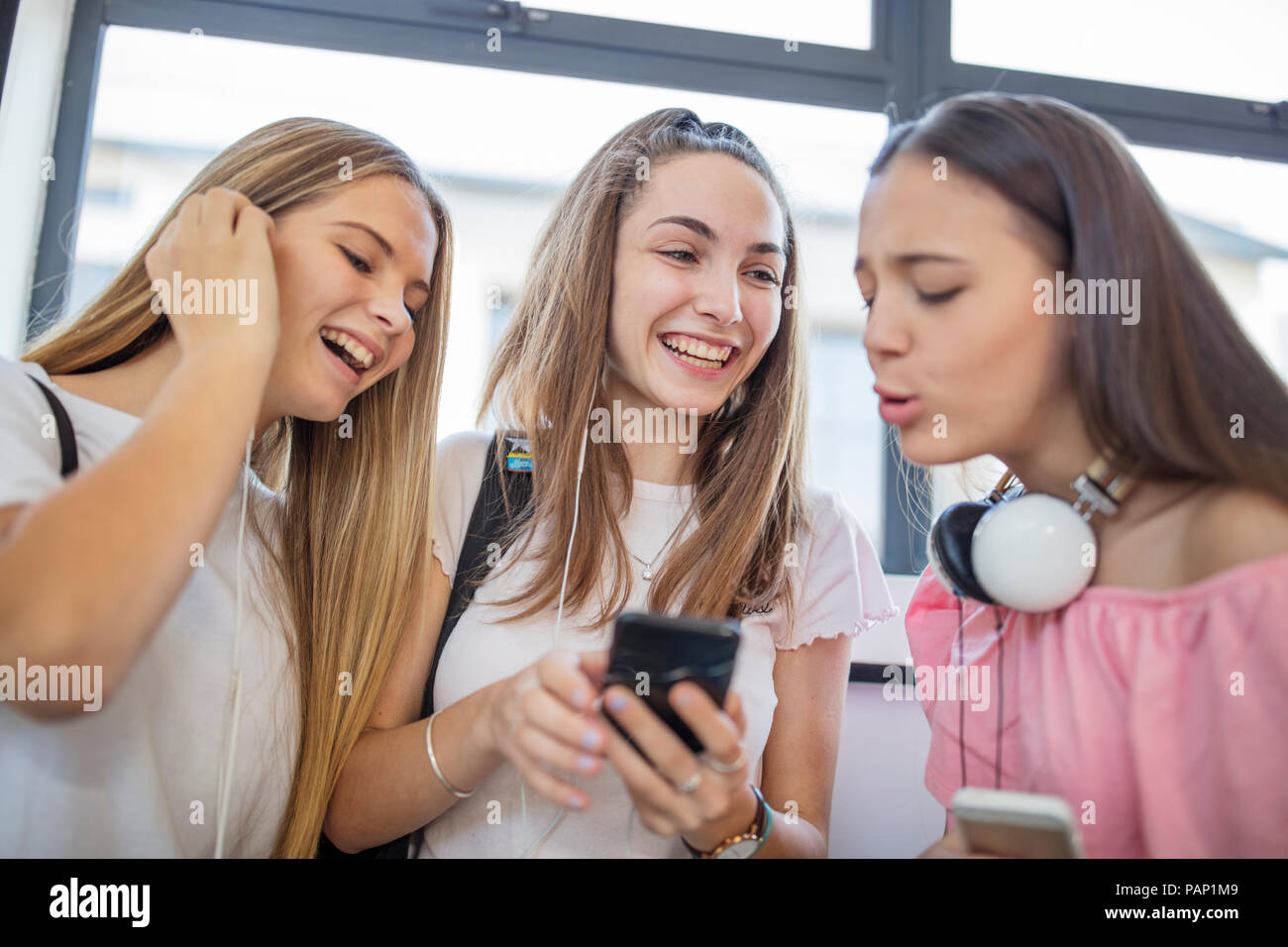 Happy teenage girls using cell phones in school Stock Photo